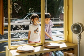 Enfants observant l’extérieur par une fenêtre, image illustrant la protection de l’enfance